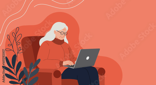 Smiling senior woman uses a laptop in a cozy armchair, representing digital literacy, online connection, and modern elder lifestyle at home.