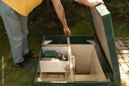 Man checking modern septic tank system outdoors.