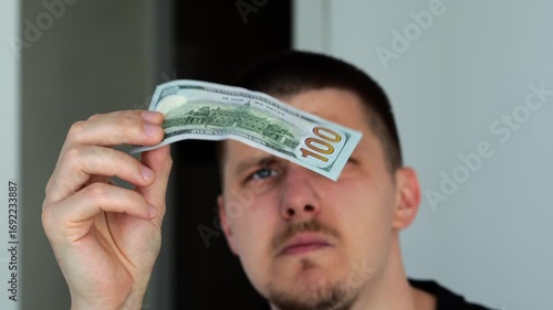 counterfeit money.
Checking the watermark on cash.
Banknote without a watermark.
Fake money in the hands of a guy.
A deceived person looks at a piece of paper that looks like money