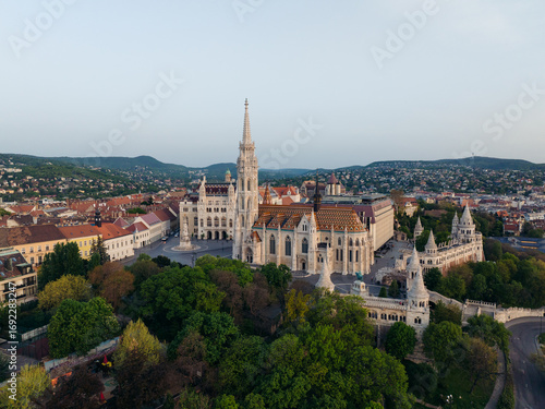 Aerial view of Matthias Church and Fisherman's Bastion stand majestically amidst lush greenery, bathed in the soft light of dawn, Budapest, Budapest, Hungary.