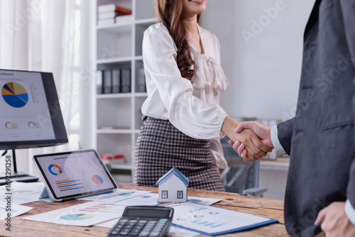 Businesswoman shaking hands with a client in a modern office, celebrating the successful signing of a real estate contract for a new home purchase, symbolizing partnership and trust