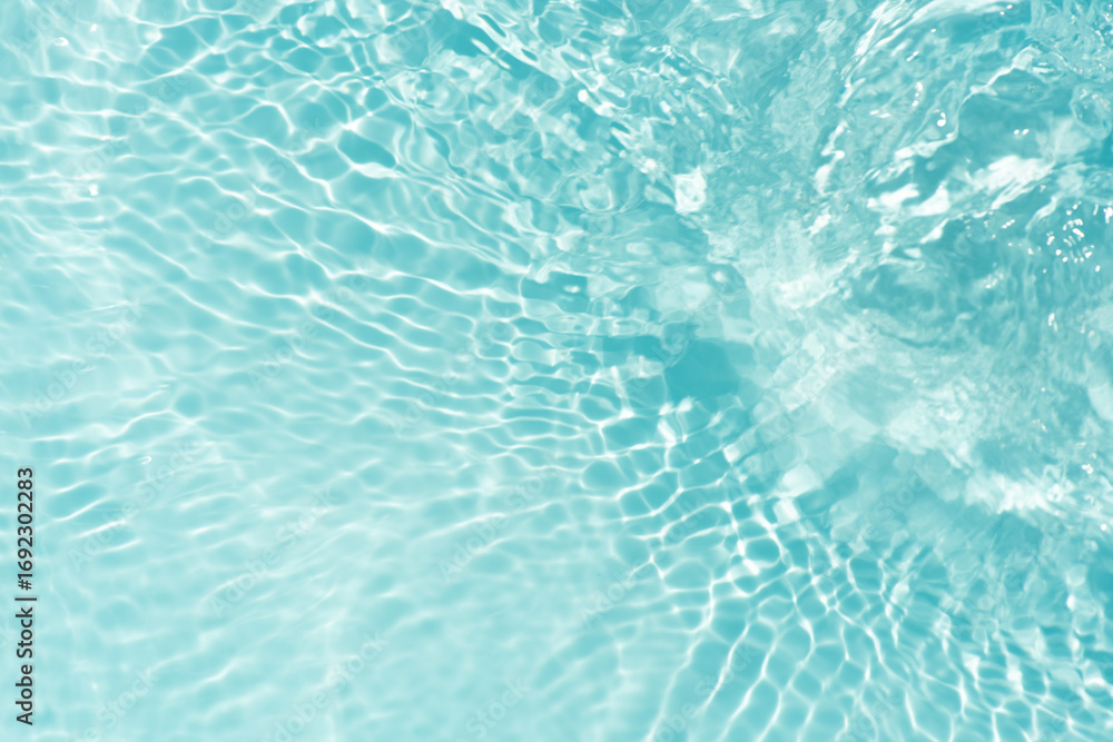 Obraz premium Blue water with ripples on the surface. Defocus blurred transparent blue colored clear calm water surface texture with splashes and bubbles. Water waves with shining pattern texture background.