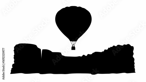 Silhouette of a hot air balloon floating above a dark landscape with canyons and rock formations view 100