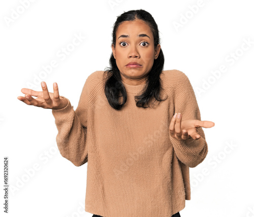 Photography Young Filipina woman doubting and shrugging shoulders in questioning gesture