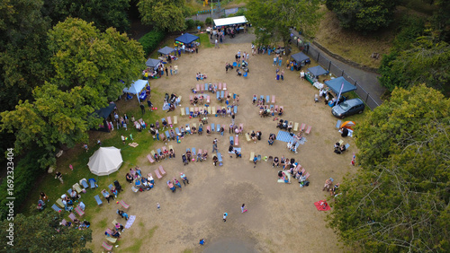 New Brighton, United Kingdom - 22 August 2025: Aerial view of Vale Park comes alive with vibrant gatherings, tents, chairs, and stalls nestled amidst lush green trees, creating a lively scene.
