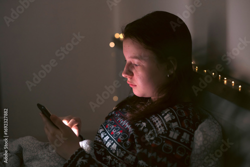 Girl using smart phone while lying on bed in bedroom