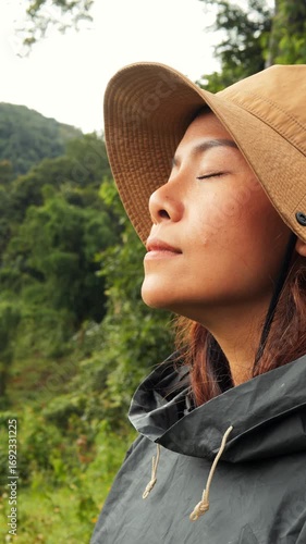 Close Up of Young Woman in Raincoat with Eyes Closed Breathing Fresh Air and Feeling Freedom in Nature