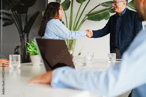Multigenerational people working inside business office - Colleagues shaking hands while greeting on a new work project - Deals and job meeting concept - Main focus on man face