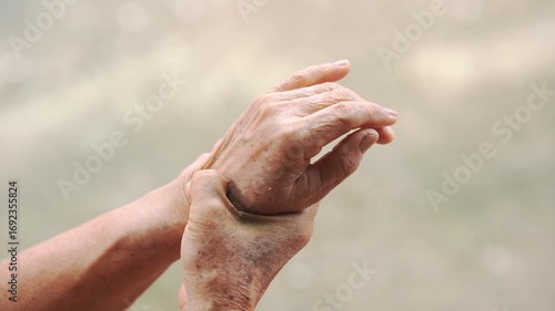 Close-up of elderly person holding their wrist, showing signs of arthritis, joint pain, or stiffness, perfect for medical, healthcare, aging, and physiotherapy-related content.