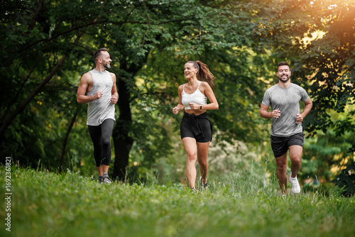 Friends enjoy running together on a sunny day in a lush green park during early evening hours