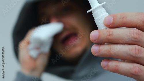 A dangerous and contagious virus in a man and a severe runny nose.
A man with a nasal spray wipes his nose during a runny nose.
Pandemic and viruses.
Dangerous viruses and respiratory diseases