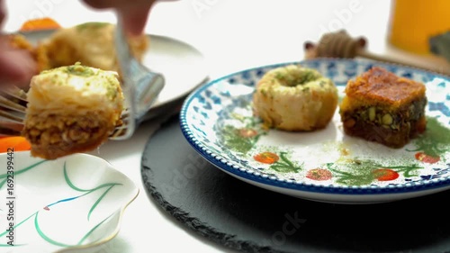 A woman serving baklava from the table onto a small plate with a fork