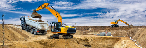 Fotografija Ein Bagger arbeitet auf einer Baustelle am Fundament für ein neues Wohnhaus - FO
