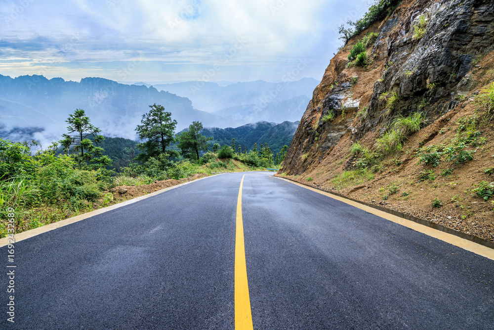 Naklejka premium Empty asphalt road and mountain with a beautiful and misty background