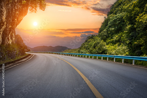 Tableau sur toile Winding asphalt road curves through a scenic mountain pass with lush green fores