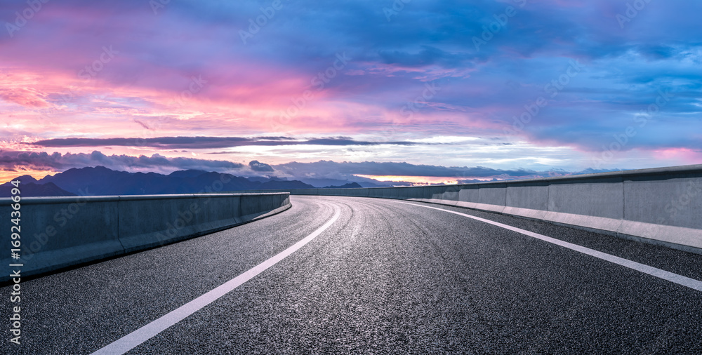 Naklejka premium Empty asphalt highway road and mountain landscape at dramatic sunset