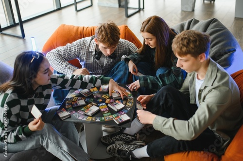 Fotografie Group of teenagers playing board game at home