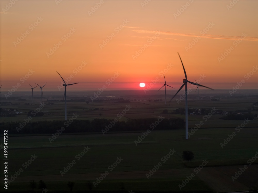 Obraz premium A wind turbine at sunrise, bathed in warm sunlight. Wind energy generates clean, renewable, and emission-free power.