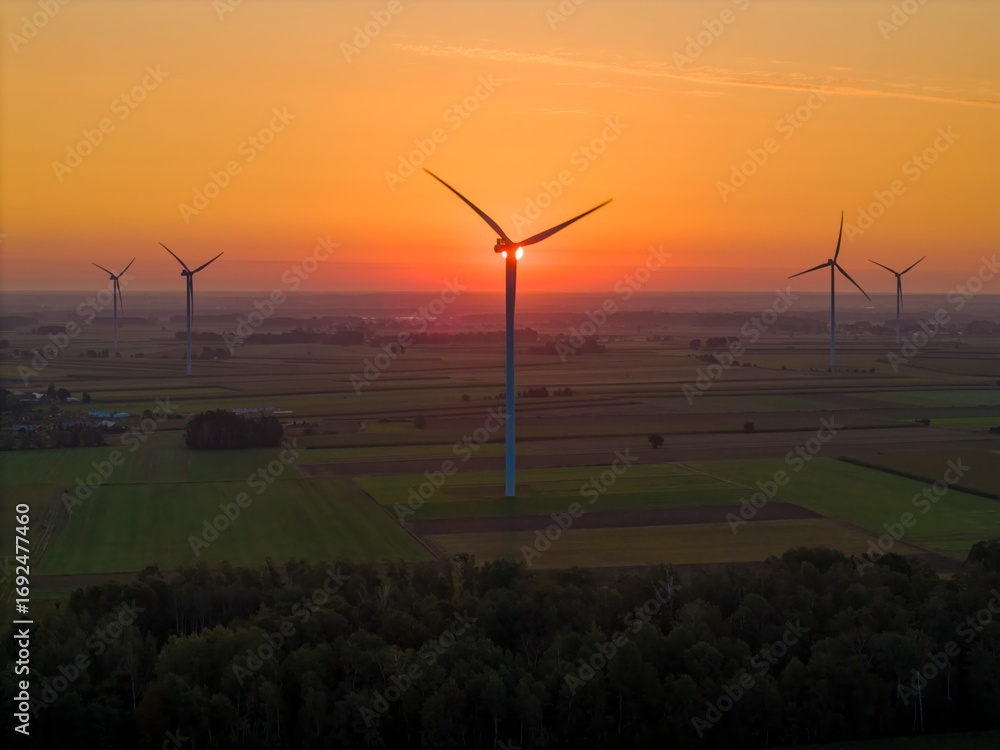 Obraz premium A wind turbine at sunrise, bathed in warm sunlight. Wind energy generates clean, renewable, and emission-free power.