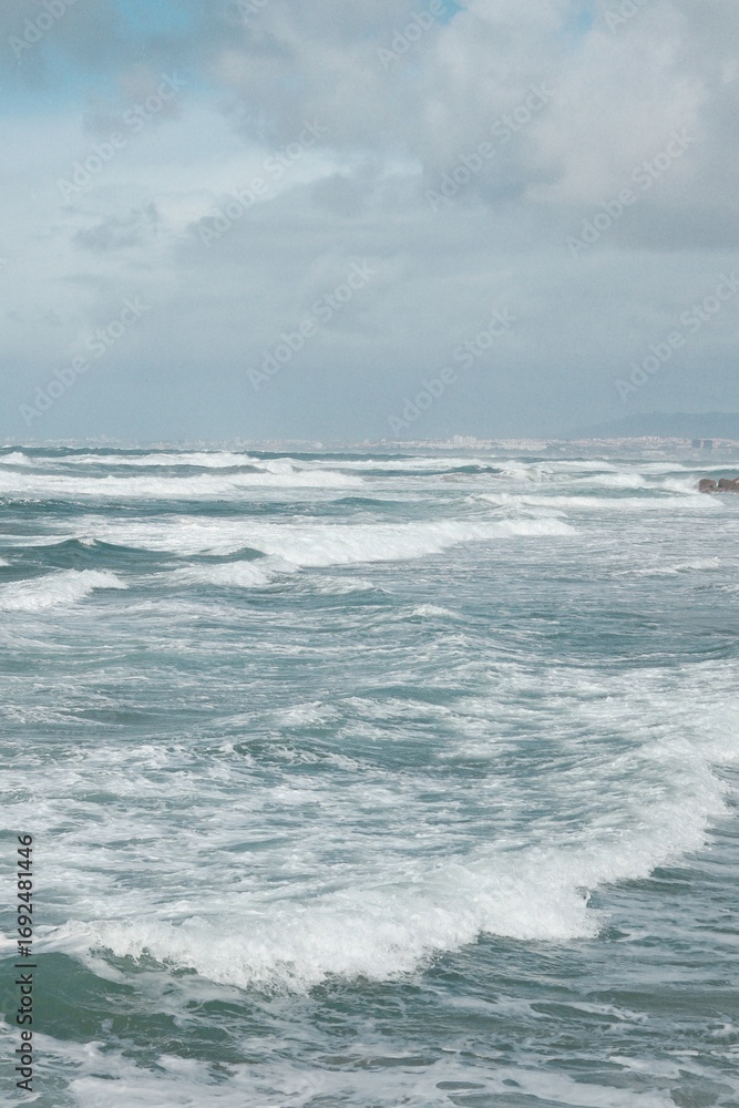 Fototapeta premium Scenic Ocean and Beach View in Costa da Caparica, Portugal, People Walking Along Shoreline at Sunrise or Sunset, Calm Waves and Atmospheric Coastal Landscape, Travel and Nature Photography
