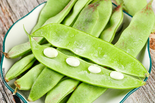 Fresh Green Pea Pods with White Beans in Bowl on Wooden Background