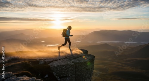 Silhouette of a trail runner on a mountain peak at sunrise.