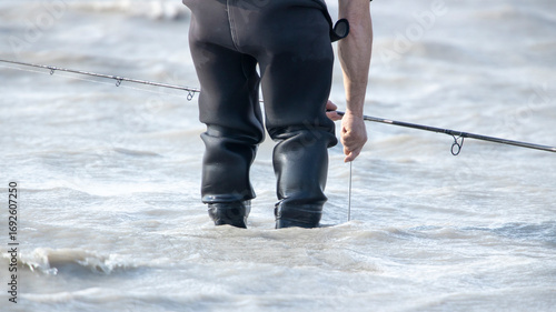 Angler in Watthose beim Fischen – Freizeitfischer im Wasser mit Angelrute, Symbol für Geduld, Ruhe und Naturverbundenheit