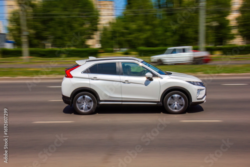Dynamic white SUV speeding down a city street on a sunny day