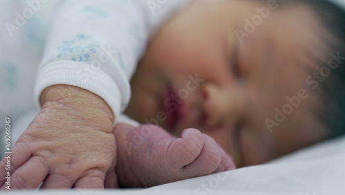 Fotografie Newborn baby sleeping with hand and foot in focus, emphasizing the delicate and
