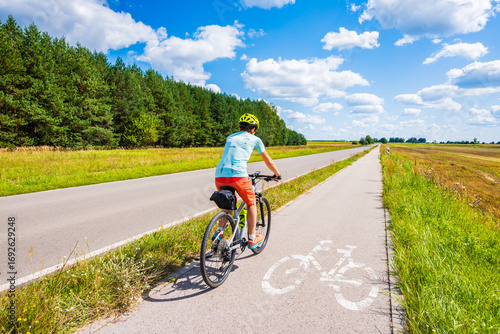 Female tourist biker riding on beautiful cycling road, Roztocze region, Poland
