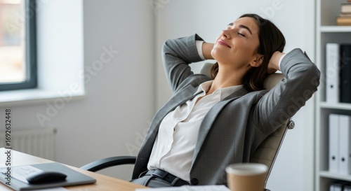 Woman relaxing in office chair with hands behind head eyes closed.