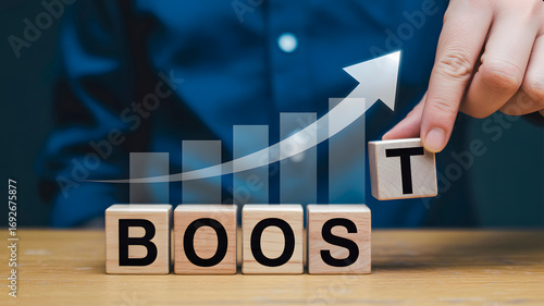 Wallpaper Mural A person's hand places the letter 'T' on blocks spelling 'BOOST', symbolizing growth and improvement with a rising graph in the background. Torontodigital.ca