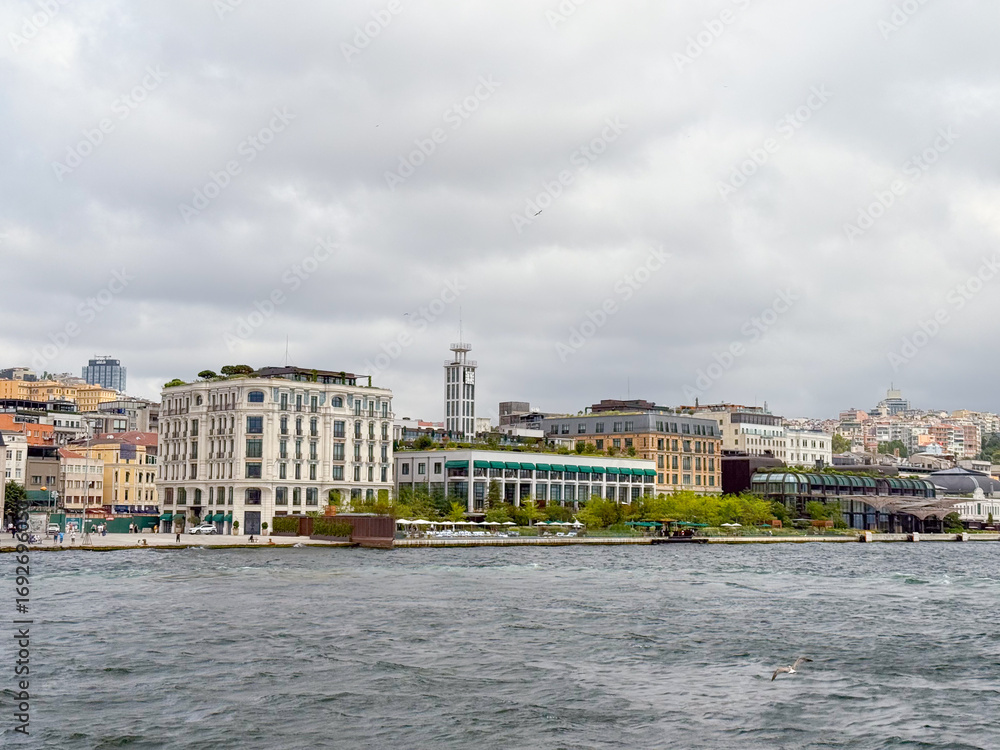 Fototapeta premium City waterfront view with historic hotel and modern buildings. Tourism, urban lifestyle, and architectural diversity in Istanbul.