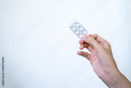 A hand displays a pharmaceutical blister pack containing a two-pill dose of medication, illustrating a moment of personal healthcare, medical choice, and responsibility for one's well-being