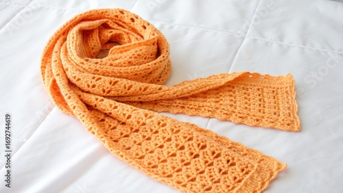 Soft orange crochet scarf on white fabric background
