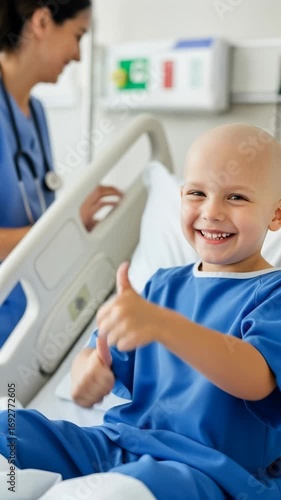 Caucasian child cancer survivor giving thumbs up while sitting in a hospital bed with nurse in the background