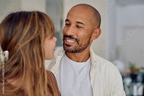 Obraz na plátně Young couple sharing a tender moment at home, smiling and gazing into each other