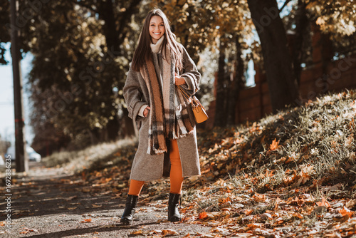Photography Chic woman in fall outfit walking through an urban park in the autumn sunshine,