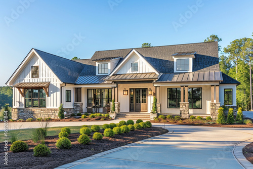 A modern southern home with clean lines, a welcoming front porch with stylish light fixtures, and a combination of stone and siding on the exterior. 