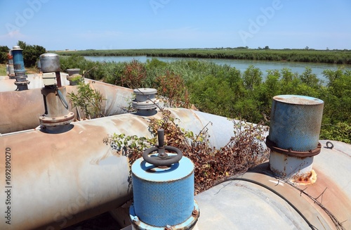 фотографія metal pumping station pipes for removing water and draining the swampy zone