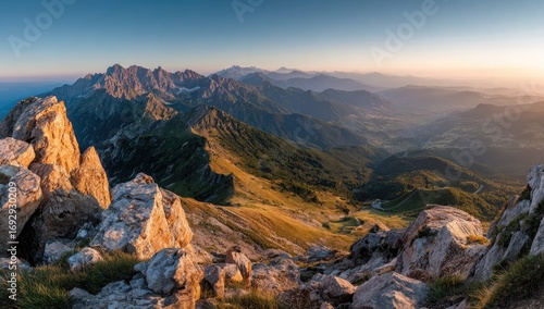 Panoramic mountain vista at sunrise.  Vast mountain range, rocky peaks, and valleys bathed in golden light