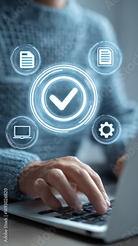 Person in Blue Sweater Typing on Laptop with Holographic Checkmark and Document Icons keyboard hands