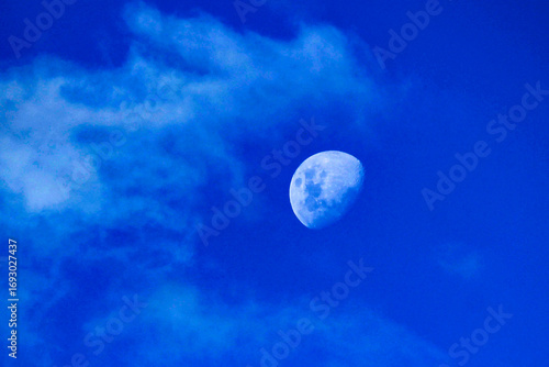 The moon peeking through fluffy white clouds