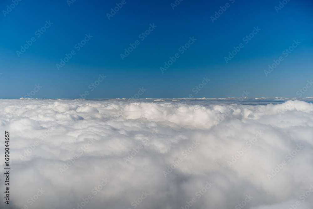 Naklejka premium Mid-Air cloudscape. A serene minimalist scene of soft, rolling cloudscape beneath a clear blue sky.