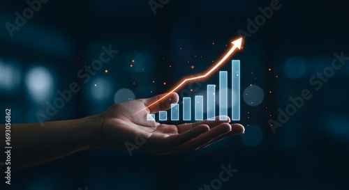 Hand holding glowing upward trending business graph with arrow