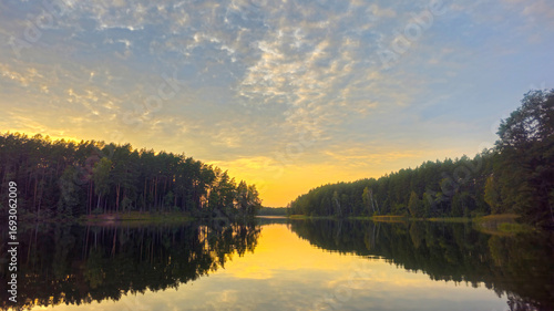 A serene sunset over a forest lake.