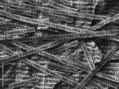 Strips of newspaper with the words Cyberbullying typed on them. Black and white. Close up.