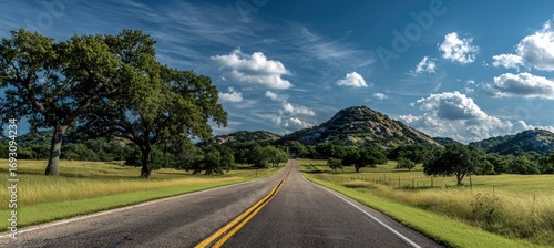 Scenic country road winds through rolling hills under a vibrant sky