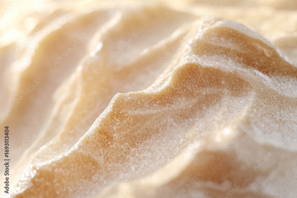 Obraz premium Close-up view of a textured, sandy beige surface resembling dunes or a creamy substance.