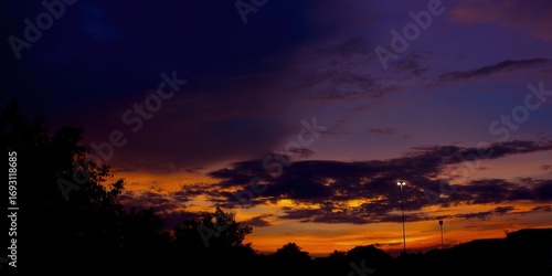 The sky glows with vibrant sunset colors, casting a dramatic silhouette.